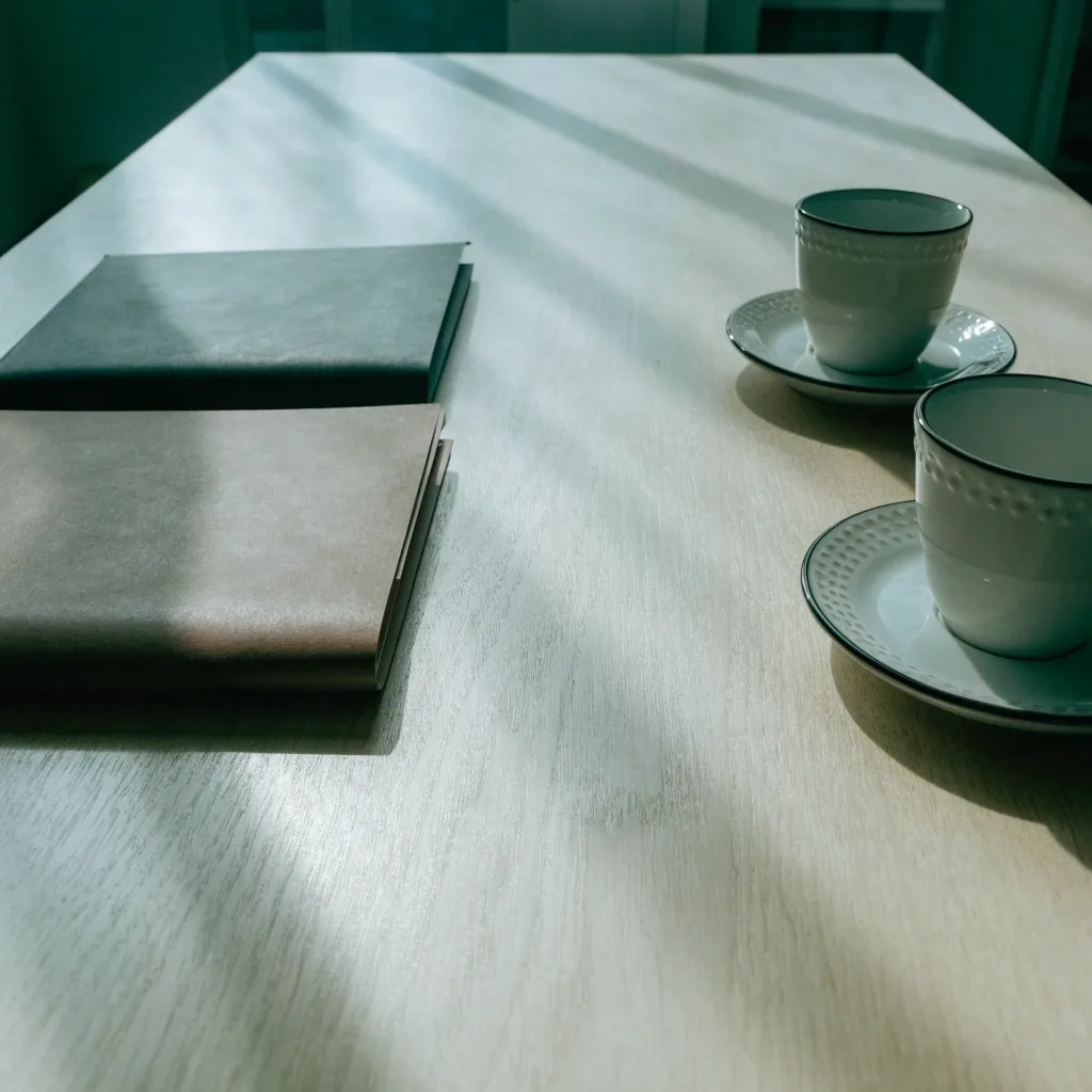 Mesa de reunión con dos carpetas cerradas y dos tazas bajo luz cenital fría
